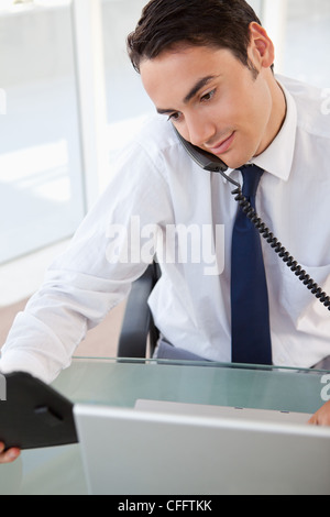 Businessman looking his agenda while making a call Stock Photo