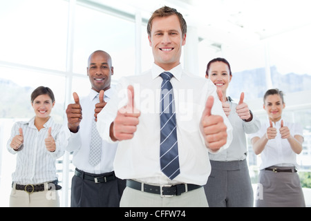 Businessman and his team giving thumbs up Stock Photo