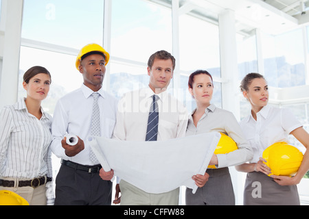 Architects with a blueprint analyzing the progress on the building site Stock Photo