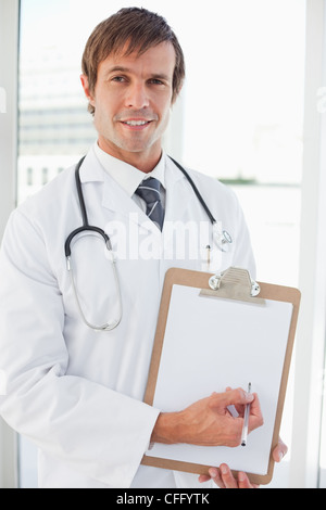 Smiling doctor pointing his clipboard with a ballpoint pen Stock Photo