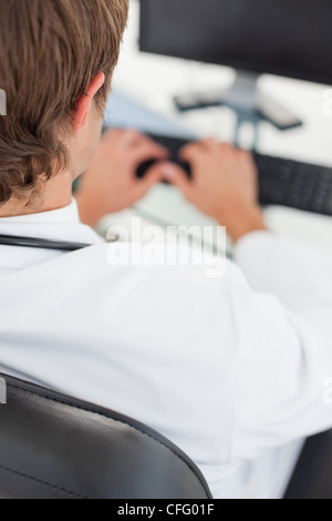 Rear view of a doctor working on his computer Stock Photo