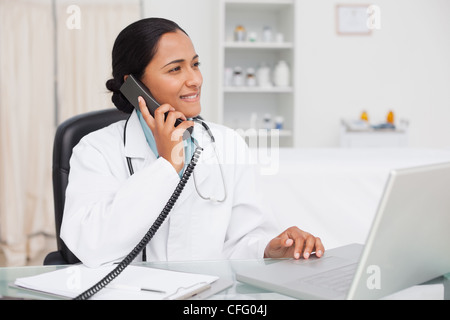 Smiling doctor looking away while talking on her office Stock Photo