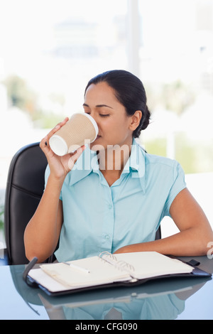 Young secretary drinking coffee while working Stock Photo