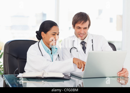 Two smiling doctors talking while sitting at the desk Stock Photo