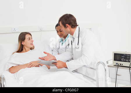 Serious doctors talking with a patient lying in a hospital bed Stock Photo