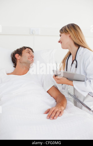 Smiling doctor looking at her patient while standing next to his hospital bed Stock Photo