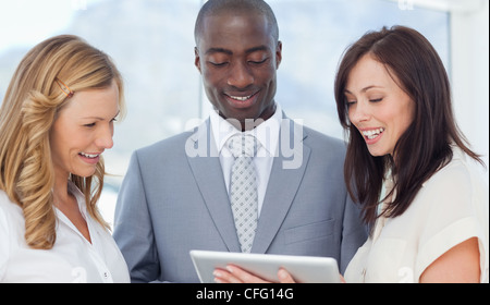 Three friends smiling while looking at a tablet Stock Photo