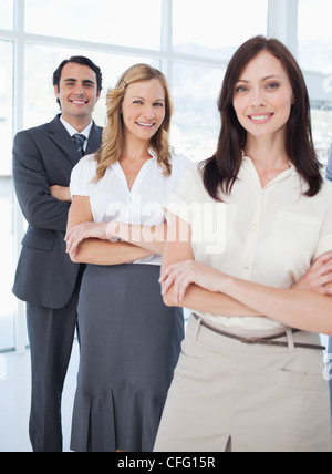 Three smiling colleagues standing behind each other with their arms crossed Stock Photo