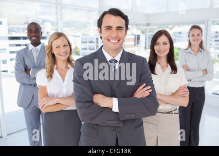 Businessman smiling while standing in front of his colleagues Stock Photo