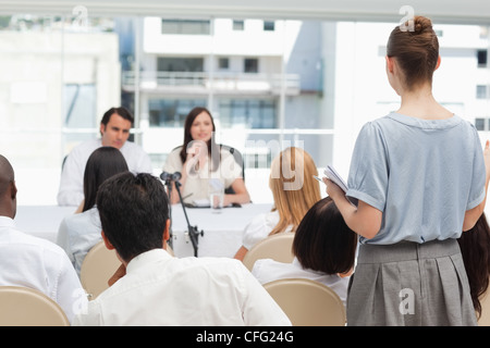 Woman holding a book as is looking at two business people Stock Photo