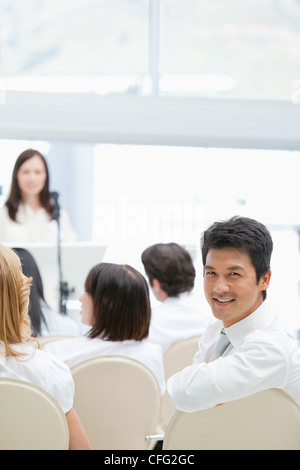 Businessman smiling while looking behind him during a speech Stock Photo
