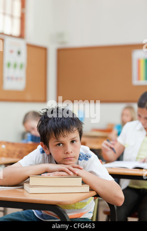 Sad looking student leaning on a pile of books Stock Photo