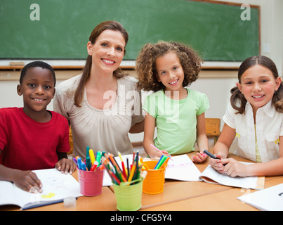 Smiling teacher sitting together with her students Stock Photo