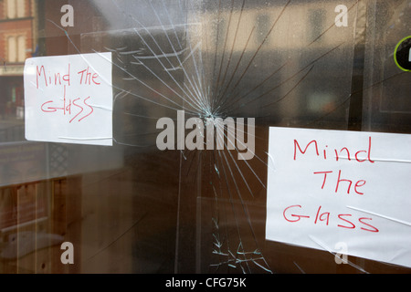 large broken cracked pane of glass with handwritten mind the glass signs county antrim northern ireland uk Stock Photo