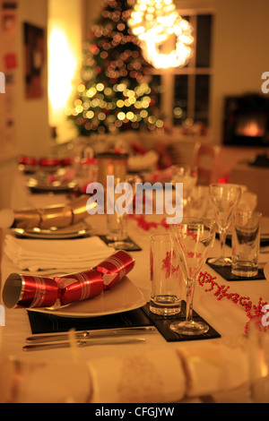 Table laid for Christmas dinner with crackers, christmas tree and decorations Stock Photo