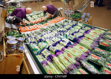 Supermarket employee stocking vegetables Stock Photo