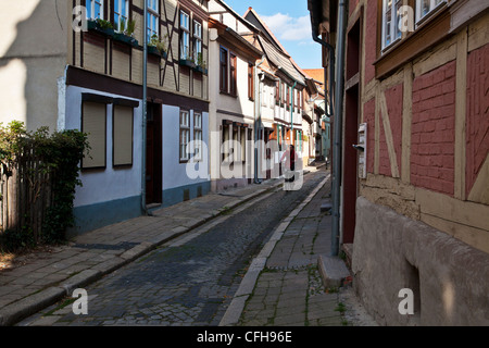 Woman cycling down a narrow cobbled street in the UNESCO German town of Quedlinburg, Saxony-Anhalt, Germany, EU Stock Photo