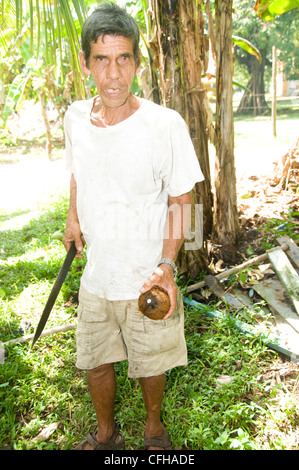 man machete cutting fresh coconut for milk Nicaragua Corn Island Central America Stock Photo