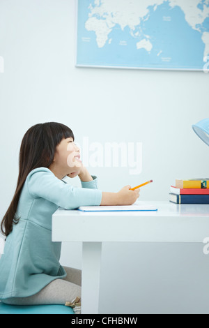 A smiling girl holding a pencil over a book Stock Photo - Alamy