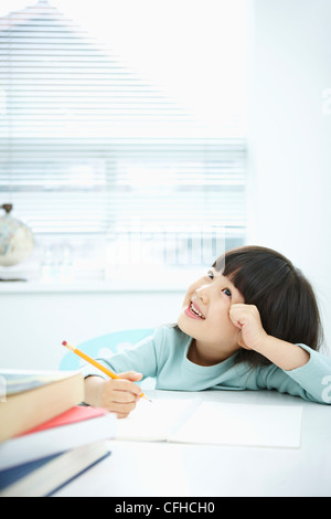 A smiling girl holding a pencil over a book Stock Photo - Alamy