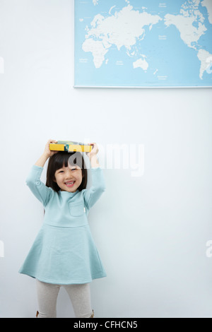 A girl holding up books over her head with the world map Stock Photo ...