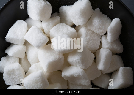 Pile of white sugar cubes in black bowl Stock Photo
