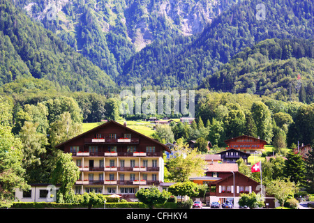 Swiss chalet surrounded by green trees and mountain Stock Photo