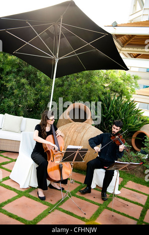 Two musicians play cello and violin on a terrace at Hotel Arts, Barcelona, Spain Stock Photo
