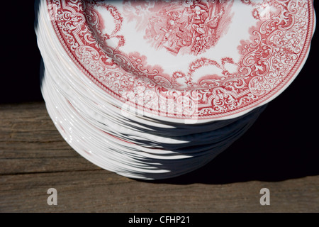 A stack of china plates on an old wooden table. Stock Photo