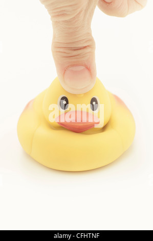 Thumb pressing on head of rubber duck Stock Photo