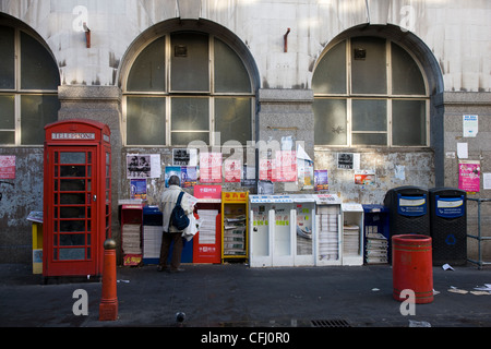 People collecting and reading free Chinese newspapers from a news stand in Chinatown, London Stock Photo