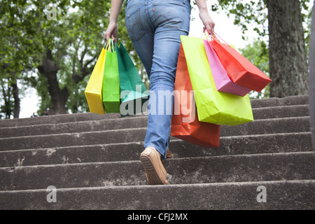 Woman holding shopping bags and going up stairs Stock Photo