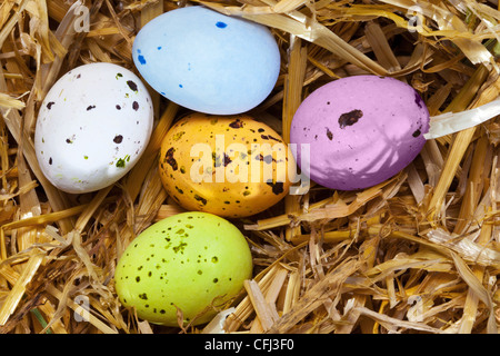 Photo of five speckled candy covered chocolate easter eggs in a straw nest. Stock Photo