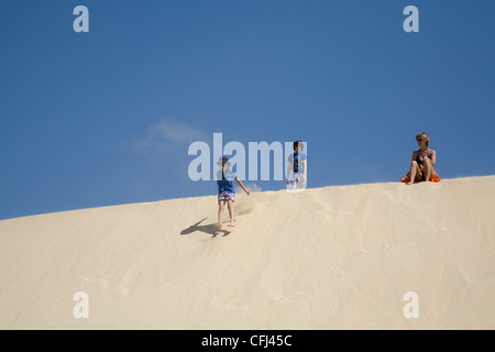 Boa Vista Cape Verde Mother sitting son standing on top son jumping down sand dune of Praia Chaves Stock Photo