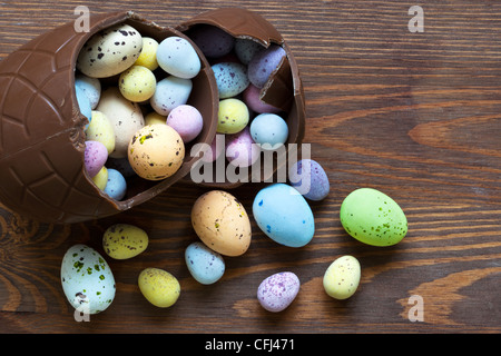 Still life photo of a large broken chocolate easter egg full of mini candy covered eggs in various pastel colours. Stock Photo