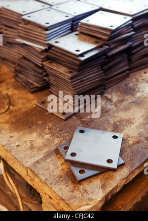 Grunge rusty rectangle metal plates with round holes placed on wooden textured board Stock Photo