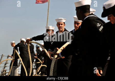 NORFOLK (March 13, 2012) Sailors assigned to the Deck department aboard the Arleigh Burke class guided-missile destroyer USS Porter (DDG 78) heave in mooring lines before departing Naval Station Norfolk. Porter is deploying as part of the Enterprise Carrier Strike Group to support maritime security operations and theater security cooperation efforts in the U.S. 5th and 6th Fleet areas of responsibility. Stock Photo