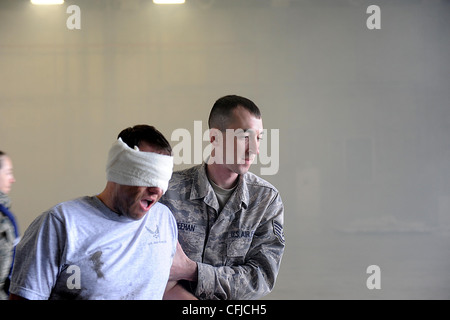 U.S. Air Force Staff Sgt. Daniel Meehan, 18th Component Maintenance Squadron technician, helps a victim escape from a smoke filled hangar during a training scenario on Kadena Air Base, March 14, 2012. Kadena is participating in a local operational readiness exercise to prepare Airmen for future contingencies Stock Photo