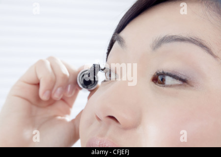 Young woman putting on mascara Stock Photo