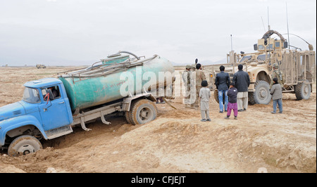 Personal security detail soldiers, assigned to Headquarters Company, 37th Infantry Brigade Combat Team, on the way back from a mission, stop to help a local Afghan farmer pull his truck out of the mud near Mazar-e-Sharif, Afghanistan, March 10, 2012. The 37th Infantry Brigade Combat Team is deployed to Afghanistan in support of Operation Enduring Freedom. Stock Photo