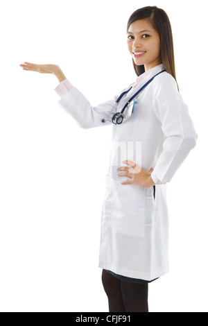 Happy cheerful beautiful Asian young Doctor holding her hand out and showing copy space for your product. Stock Photo