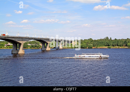 small promenade motor ship on big river near bridge Stock Photo