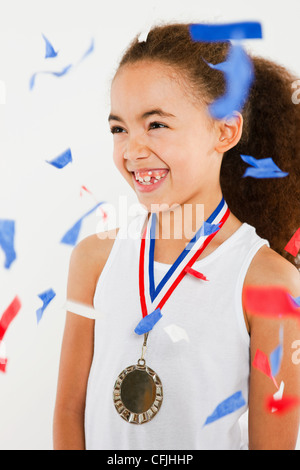 Girl wearing medal with ticker tape falling Stock Photo