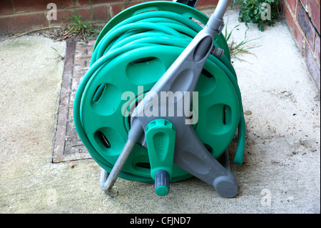 Hose pipe on a reel in garden laying dormant with the hosepipe ban in many areas of the country Stock Photo
