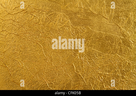 texture of the wall, covered with a thin gold foil, with beautiful folds and fissures Stock Photo