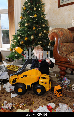 Child opening Christmas presents on Christmas day infront of Christmas tree Stock Photo