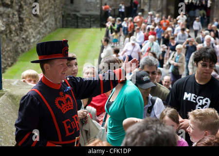 Yeoman Guard or Beefeater giving a guided tour commentary to a crowd of tourists at the Tower of London, London Stock Photo