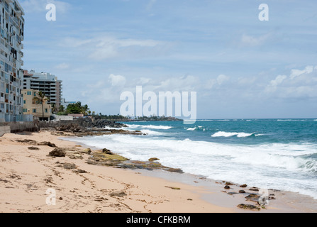 A beach beside the sea and some run down hotels and housing in San Juan, Puerto Rico Stock Photo