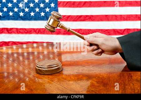 A judge’s gown and gavel with sound block on deep, rich colored wooden desktop and American flag Stock Photo