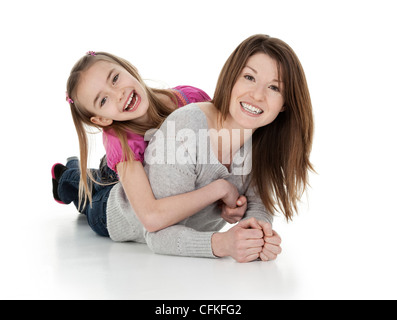 Pretty young mother and daughter cuddling playfully on white background. Stock Photo